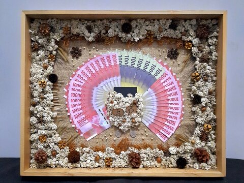 Artistic Indonesian Mahar wedding gift with rupiah banknotes arranged inside decorative glass frame.