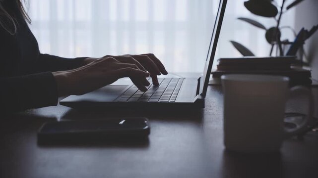 dark silhouette woman hands close-up typing text on keyboard, using working on laptop late overtime, sitting at desk black shadow room window backlit evening dusk. girl student is writing thesis 4k