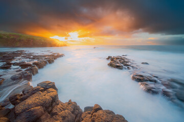 Coastal Inlet at Sunset with Storm Clouds