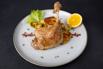 Duck leg confit with Brussels sprouts, baked potatoes, thyme and orange. Traditional French...