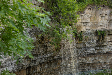Valaste Waterfall, the highest in Estonia, cascading over limestone cliffs in Ida-Viru County. Lush green foliage frames the rugged rock wall, showcasing iconic Baltic sightseeing and natural beauty.