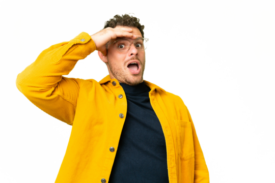 Brazilian man over isolated chroma key background doing surprise gesture while looking to the side