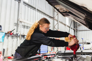 female mechanic filling up car with oil in workshop