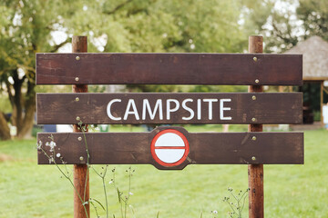 Wooden campsite sign with white letters and no entry traffic symbol. Outdoor rustic information...