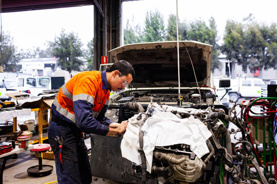mechanic in high-vis working in industrial workshop repairing mining fleet vehicle engine