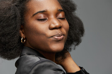Portrait of a joyful Black woman with voluminous natural hair, dressed in a stylish blazer, exuding...