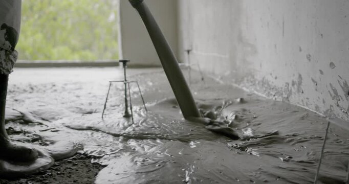 Close-up of liquid screed being poured onto a floor during construction.