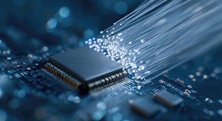 Close-up of a dark circuit board with a microchip at its center.  Fiber optic cables extend outwards from the chip.  Blurred background