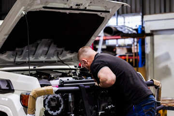 Australian man installing bull bar onto vehicle in mechanic workshop