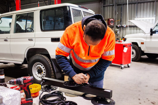 man working on upgrades to light bar fitting for vehicle in mechanic workshop