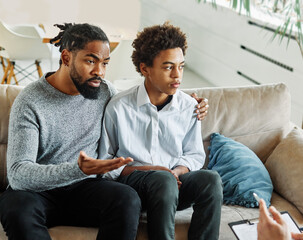 Father with his teenage son at meeting with social worker, psychologist discussing mental health...