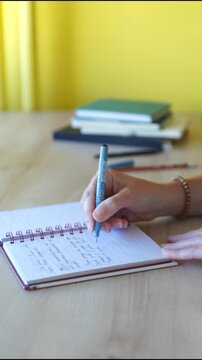 A woman is writing notes in a notebook with beautiful handwriting close-up