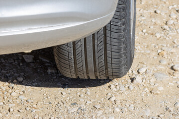 Car tire standing on gravel road in sunny day