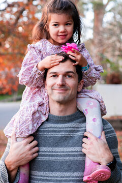 Father Carrying Daughter on Shoulders During Autumn Walk in Suburban Street