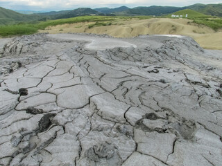Mud volcano landscape in Buzau, Romania. Grey dried mud with surface cracks, arid textures, barren terrain, geological patterns, erosion marks, natural formation, cracked earth, dry environment. © Yuliia