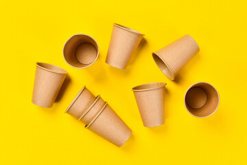 Top view of a Brown coffee paper cup. Set of paper cups on a yellow background. The concept of protecting the world from plastic waste, fighting environmental pollution. Free space for text.