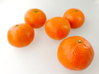 Five fresh oranges with bright glossy skin placed on a white background, symbolizing healthy food, natural freshness, tropical fruit, and a source of vitamin C.