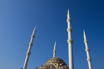 The tall, white minarets and central dome of the Mosque stand out against a clear, deep blue sky