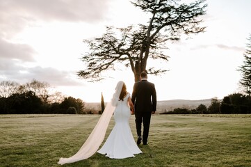 Winter wedding bride and groom walking in to the sunset