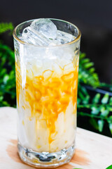 Close-up of an iced caramel milk drink in a tall glass with ice cubes, milk, and caramel drizzle on the sides.
