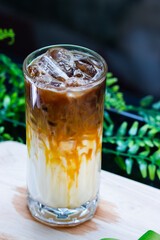 Close-up of iced caramel macchiato in a tall glass, layered with milk, caramel drizzle, and espresso over ice cubes.