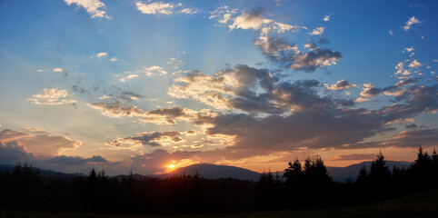 Serene evening sky with hues of blue and soft pink clouds as sun sets. Horizon glows gently,...