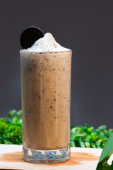 Iced Oreo coffee frappe in a tall glass topped with whipped cream and an Oreo cookie, blended with...