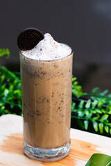 Iced Oreo coffee frappe in a tall glass topped with whipped cream and an Oreo cookie, blended with crushed cookies for a creamy texture.