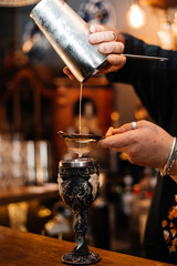 Bartender Straining Cocktail into Ornate Goblet