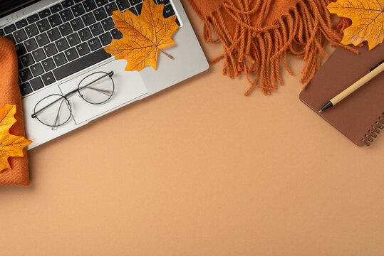 Autumn-themed flat lay featuring a laptop, glasses, scarf, notebook, and fall leaves