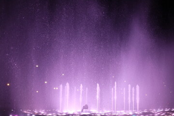 Abstract background. Motion blurred colorful fountain at night