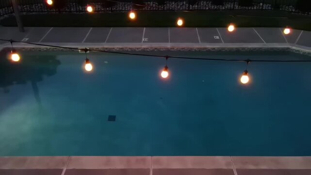 Swimming pool with water and string lights at twilight for summer lifestyle outdoor background.