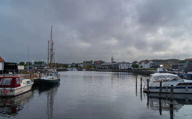 Boats and yachts docked in Thisted marina under dramatic clouds. View of the harbor and town with...