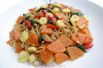 Flavorful vegetarian stir fried instant noodles with fresh basil leaves. vibrant dish offering...