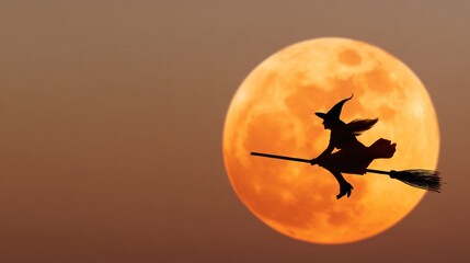 Fototapeta premium A silhouette of a witch flying on a broomstick against a huge orange moon 