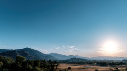 A vast landscape unfolds, showcasing a serene vista of rolling hills, lush green trees, and a clear, vibrant blue sky, illuminated by a golden sunrise.