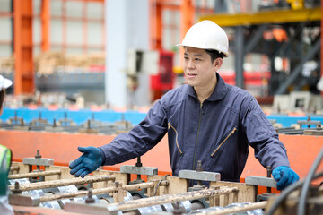 Engineer or worker checking rolling machine and talking with coworker in the metal sheet factory