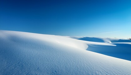 wavy snow dunes under a clear blue sky showing pristine winter landscape