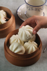 hand on frame. Bakpao Coklat, chinese steamed buns with chocolate paste on bamboo basket
