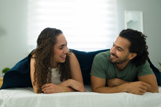 Charming couple relaxing and talking in bed together - Powered by Adobe