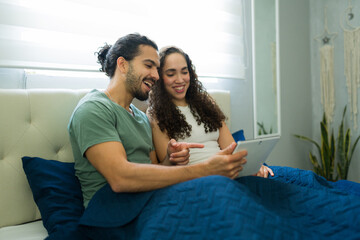 Charming couple watching tablet in bed together