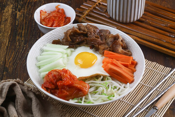 Korean bibimbap with kimchi, spinach, egg, and rice on dark plate
