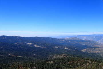 Panoramic view of the mountain range covered with dense coniferous forest. The photo was taken in clear sunny weather