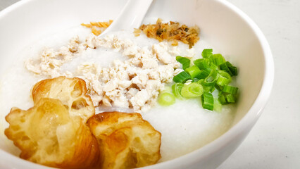 A delicious bowl of rice porridge topped with savory minced chicken, spring onions and pickled radish.