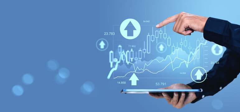 Businessman analyzing digital stock market chart with finger and tablet on blue background, showing growth and success concept.