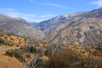 Mountain landscape in Kings Canyon National Park, California. Dry shrubs and a road are visible in the foreground