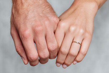 Fototapeta premium Close-up of couple holding hands with engagement ring on woman’s finger, romantic love and relationship detail shot symbolizing commitment, marriage proposal, togetherness, and affection
