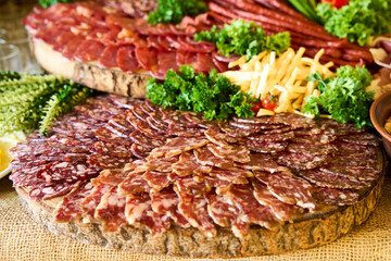 Artfully arranged charcuterie board featuring a variety of cured meats and fresh greens for an...