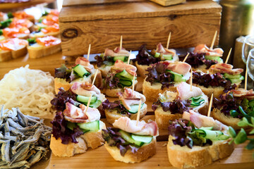 Deliciously crafted canapés arranged beautifully on a rustic wooden table at a lively gathering