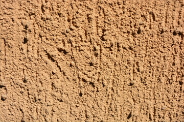 Construction, repair work, lining, covering walls with the latest materials. Brown wide background with voluminous granules, drops, textured sand on the street wall.